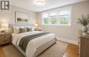Windsor apartment for rent - A bedroom with a large bed and a window with a view of greenery outside.
