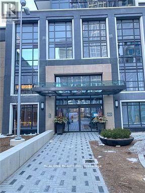 Toronto (Islington-City Centre West) condo for rent - A modern building with a glass entrance and a stone walkway leading to it.