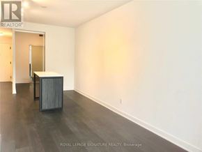 Toronto (Waterfront Communities) condo for rent - A room with a wooden floor and white walls, with a doorway leading to another room.
