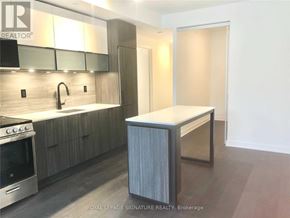 Toronto (Waterfront Communities) condo for rent - A modern kitchen with a stainless steel oven and wooden cabinets.