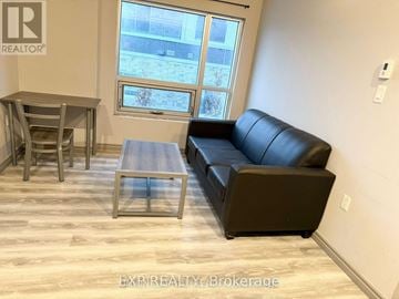 Waterloo condo for rent - A living room with a black leather couch, a wooden coffee table, and a dining table with chairs.