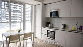 Toronto (Waterfront Communities) condo for rent - A modern kitchen with a dining table and chairs.