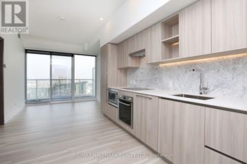 Toronto (Waterfront Communities) condo for rent - A modern kitchen with wooden cabinets and a marble backsplash.
