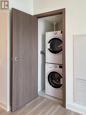 Toronto (Waterfront Communities) condo for rent - A modern washing machine is built into a wooden cabinet in a room.