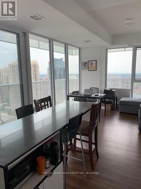 Mississauga (Hurontario) condo for rent - A kitchen with a table and chairs in front of a window overlooking a cityscape.