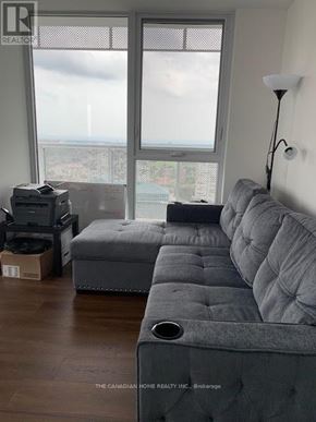 Mississauga (Hurontario) condo for rent - A grey couch sits in a room with a large window overlooking a cityscape.
