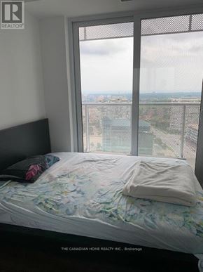 Mississauga (Hurontario) condo for rent - A bedroom with a large window overlooking a cityscape.
