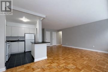 Toronto (Thorncliffe Park) condo for rent - A kitchen with white cabinets and a black countertop is shown in the image.
