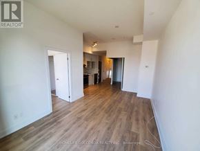 Toronto (Don Valley Village) condo for rent - A room with wooden flooring and white walls, with a doorway leading to another room.