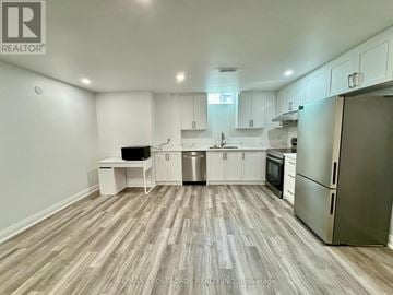Markham (Berczy) apartment for rent - A kitchen with white cabinets and a wooden floor.