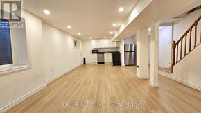 Mississauga (Malton) apartment for rent - A spacious room with wooden flooring and a staircase on the right side.