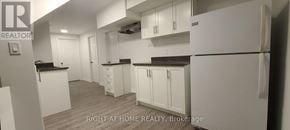Toronto (Woburn) apartment for rent - A white kitchen with a refrigerator, cabinets, and a counter.