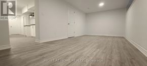 Toronto (Woburn) apartment for rent - A spacious room with wooden flooring and white walls, labeled as a brokerage by Right at Home Realty.
