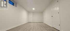 Toronto (Woburn) apartment for rent - A spacious room with white walls and a wooden floor.