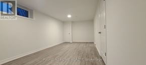 Toronto (Woburn) apartment for rent - A spacious room with wooden flooring and white walls, with a door on the right side.