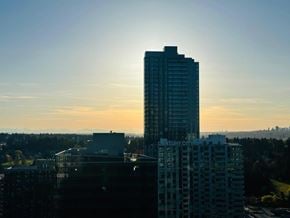 Surrey apartment for rent - A tall building stands in the foreground with a sunset in the background.