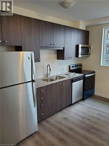 Kitchener condo for rent - A modern kitchen with a stainless steel refrigerator and dark wood cabinets.