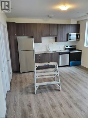 Kitchener condo for rent - A kitchen with a refrigerator, stove, and microwave.