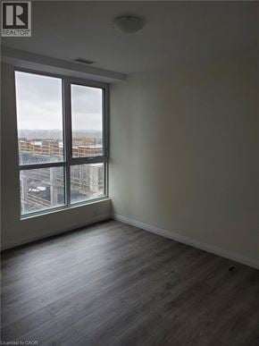 Kitchener condo for rent - A room with a large window overlooking a cityscape.