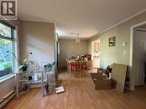 Burnaby townhouse for rent - A room with a dining table and chairs in the middle of the room with boxes on the floor.
