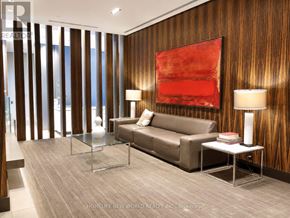 Toronto (Church-Yonge Corridor) condo for rent - A modern living room with a brown couch, a glass table, and a red abstract painting on the wall.