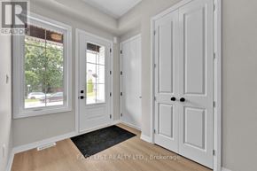 Thorold (Confederation Heights) fourplex for rent - A white door with a black handle is in the center of a room with a window and a mat on the floor.