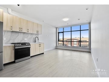 Surrey apartment for rent - A spacious kitchen with wooden cabinets and a large window overlooking a building.