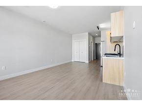 Surrey apartment for rent - A spacious room with wooden flooring and white walls, featuring a kitchenette with a sink and cabinets.