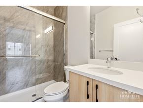 Surrey apartment for rent - A modern bathroom with a marble shower and a white toilet.