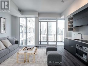Toronto (Bay Street Corridor) condo for rent - A modern living room with a grey sofa and a wooden coffee table.