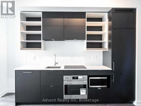 Toronto (Bay Street Corridor) condo for rent - A modern kitchen with a black refrigerator and stove top oven.