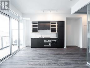 Toronto (Bay Street Corridor) condo for rent - A modern kitchen with black cabinets and stainless steel appliances.