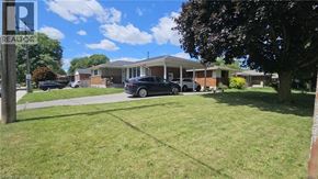 Hamilton apartment for rent - A realtor sign is in front of a grassy area with a house and cars in the background.