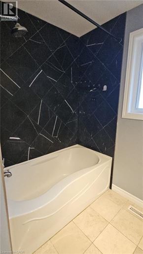 Hamilton apartment for rent - A bathroom with a black and white tiled wall and a white bathtub.