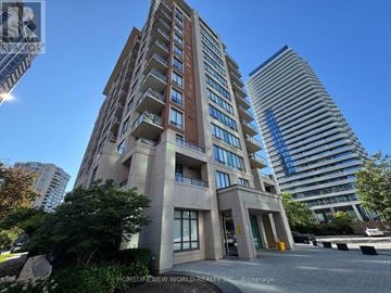 Toronto (Willowdale East) condo for rent - A tall building with a flat roof and a balcony on the second floor is surrounded by other buildings.