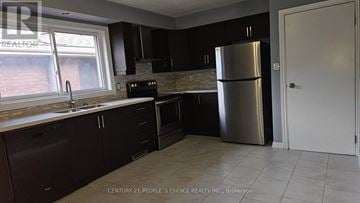 Hamilton (Rolston) apartment for rent - A kitchen with dark brown cabinets and a stainless steel refrigerator.