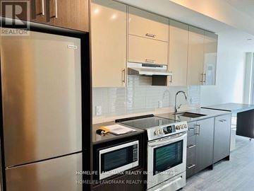 Toronto (Don Valley Village) condo for rent - A modern kitchen with stainless steel appliances and white cabinets.
