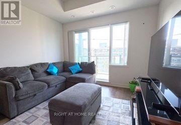 Toronto (Malvern) condo for rent - A living room with a grey couch and a small ottoman.