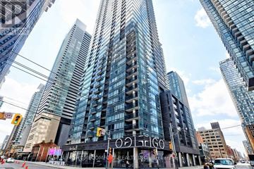 Toronto (Waterfront Communities) condo for rent - A tall building with the word "Olympia" on it is in the foreground of a city street.