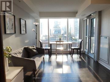 Toronto (Waterfront Communities) condo for rent - A living room with a grey couch and a table with chairs.