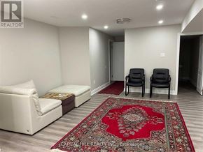 Toronto (Highland Creek) apartment for rent - A living room with a white couch, a red rug, and two black chairs.