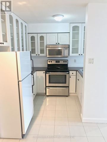 Toronto (Church-Yonge Corridor) condo for rent - A white kitchen with a refrigerator on the left and a stove top oven in the middle.