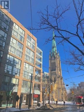 Toronto (Church-Yonge Corridor) condo for rent - A tall building with a green spire stands behind a modern building with a red sign that says "Castro".