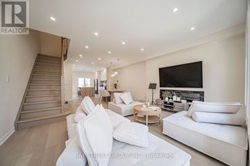 Markham (Commerce Valley) townhouse for rent - A spacious living room with white furniture and a staircase.