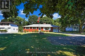 Clarington (Courtice) apartment for rent - A house with a red roof and a flag on top is surrounded by greenery.