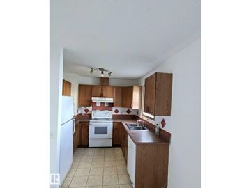 Edmonton townhouse for rent - A kitchen with white appliances and wooden cabinets.
