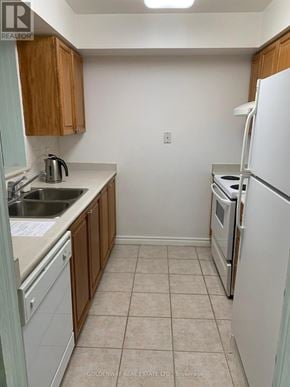Toronto (Steeles) condo for rent - A kitchen with white appliances and wooden cabinets.
