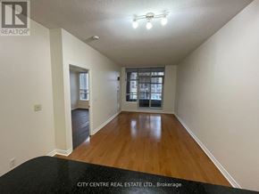 Mississauga (City Centre) condo for rent - A spacious room with wooden floors and a large window.