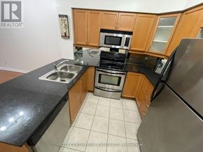 Mississauga (City Centre) condo for rent - A kitchen with wooden cabinets and black countertops.