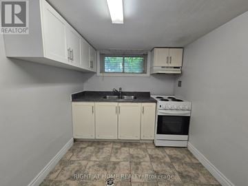 Toronto (Keelesdale-Eglinton West) apartment for rent - A kitchen with white cabinets and a black countertop.